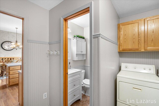 6332 Rush Creek Ct, Hudsonville, MI 49426 - bathroom with vanity, washer / dryer, toilet, a wainscoted wall, and a chandelier