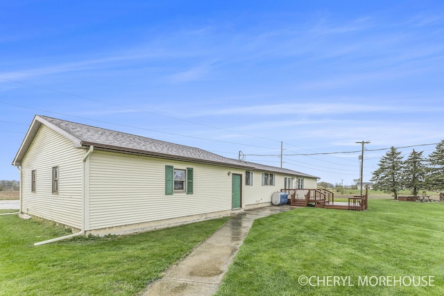 exterior space featuring roof with shingles, a yard, and a deck