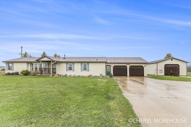 ranch-style home featuring an attached garage, a front lawn, an outbuilding, and concrete driveway