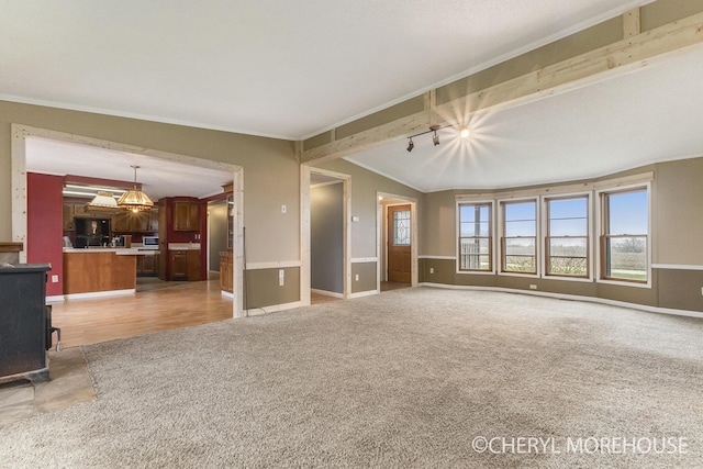 unfurnished living room with crown molding, light carpet, a wood stove, baseboards, and vaulted ceiling with beams