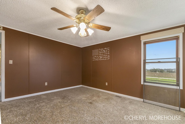 empty room with a ceiling fan, a textured ceiling, crown molding, baseboards, and carpet