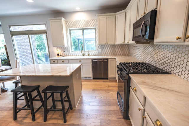 270 Fairway View Dr, Oxford, MI 48371 - kitchen featuring black appliances, a breakfast bar area, light wood-type flooring, decorative backsplash, and recessed lighting