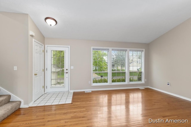 entrance foyer featuring wood finished floors, baseboards, stairway, and lofted ceiling