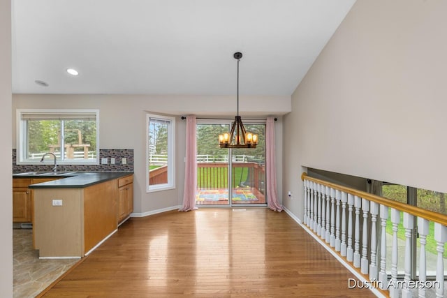 unfurnished dining area with light wood-style flooring, plenty of natural light, baseboards, a chandelier, and recessed lighting