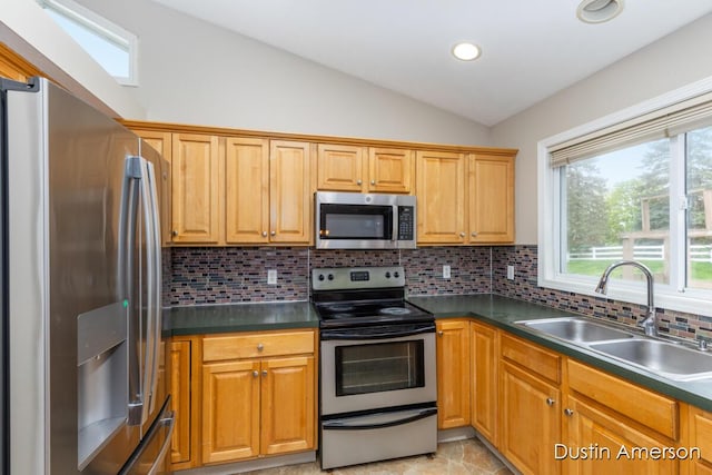 kitchen featuring stainless steel appliances, a sink, lofted ceiling, tasteful backsplash, and dark countertops