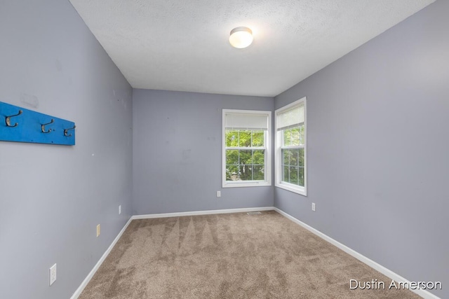 unfurnished room featuring carpet flooring, baseboards, and a textured ceiling