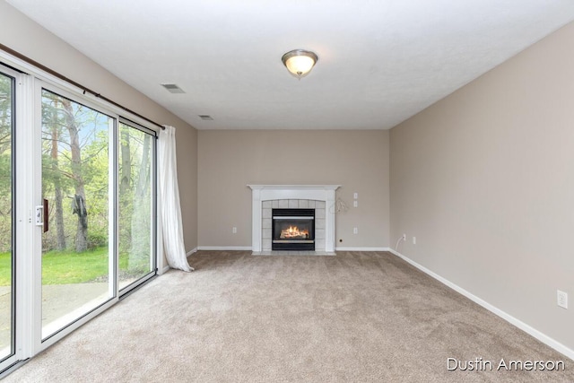 unfurnished living room with carpet floors, baseboards, and a tiled fireplace