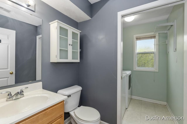 bathroom featuring washing machine and clothes dryer, toilet, baseboards, vanity, and tile patterned floors