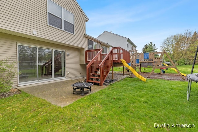 rear view of property featuring an outdoor fire pit, a playground, a lawn, and a patio