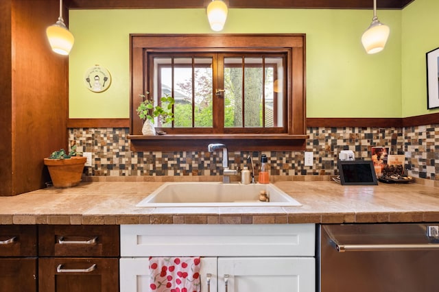 kitchen with dishwasher, a sink, tile counters, and decorative backsplash