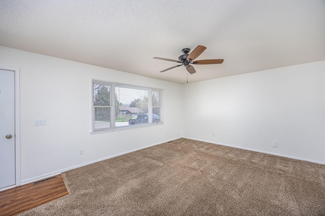 carpeted spare room with ceiling fan, visible vents, and baseboards
