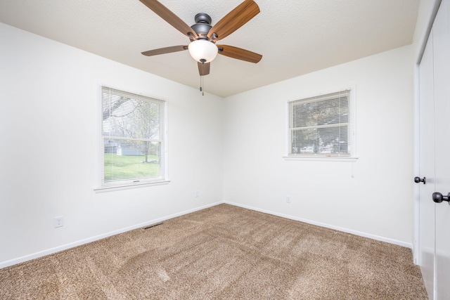 empty room with visible vents, baseboards, ceiling fan, a textured ceiling, and carpet flooring