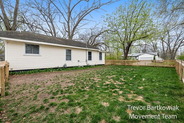 rear view of property featuring a lawn and a fenced backyard