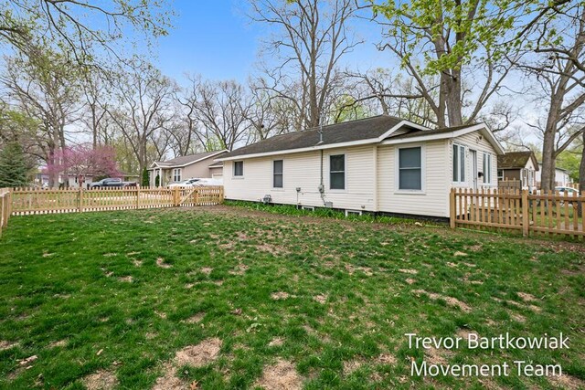 rear view of house with a lawn and a fenced backyard