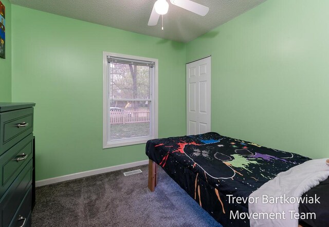 bedroom featuring a textured ceiling, dark carpet, a ceiling fan, baseboards, and visible vents