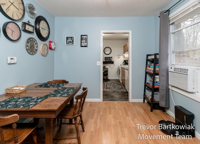 dining space with baseboards, a textured ceiling, wood finished floors, and cooling unit