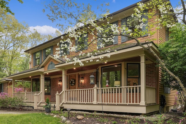 326 Greentree Ln NE, Ada, MI 49301 - view of front facade featuring covered porch and brick siding
