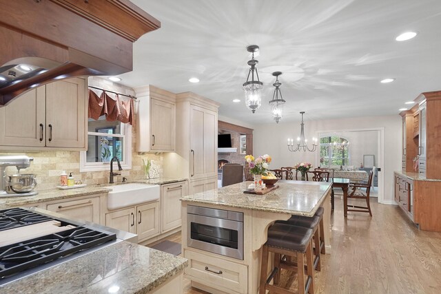 326 Greentree Ln NE, Ada, MI 49301 - kitchen with a sink, a chandelier, decorative backsplash, recessed lighting, and light stone countertops