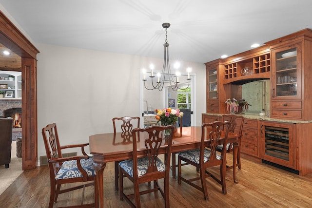 326 Greentree Ln NE, Ada, MI 49301 - dining space with a chandelier, light wood-style floors, recessed lighting, beverage cooler, and a lit fireplace