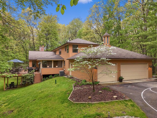 326 Greentree Ln NE, Ada, MI 49301 - view of front of house with a chimney, asphalt driveway, a front lawn, a shingled roof, and an attached garage