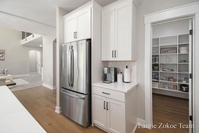 1791 Gloryfield Dr, Byron Center, MI 49315 - kitchen with freestanding refrigerator, arched walkways, light wood-style floors, backsplash, and light countertops