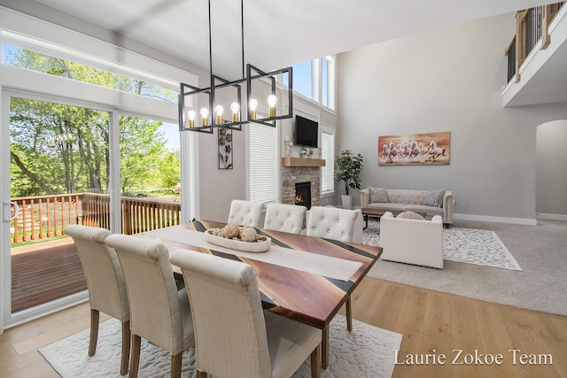 1791 Gloryfield Dr, Byron Center, MI 49315 - dining space with a chandelier, a stone fireplace, baseboards, and light wood-style floors