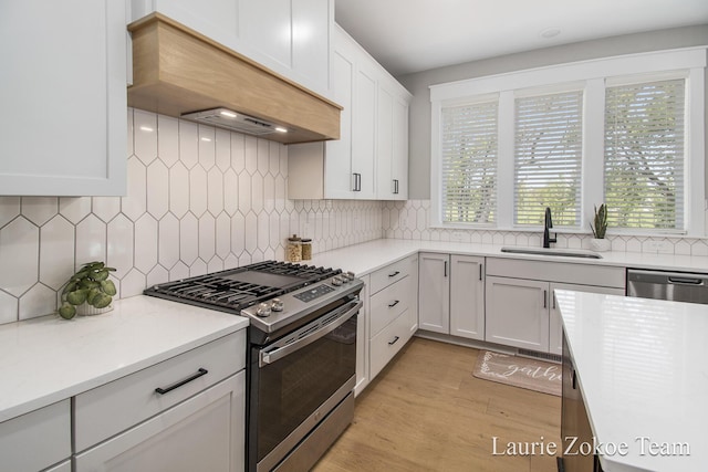 1791 Gloryfield Dr, Byron Center, MI 49315 - kitchen with stainless steel appliances, a sink, custom exhaust hood, white cabinets, and light wood-style flooring