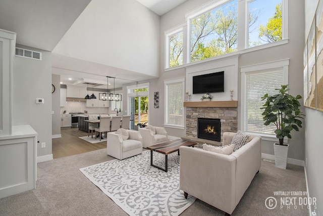 1791 Gloryfield Dr, Byron Center, MI 49315 - living area featuring a fireplace, carpet flooring, a towering ceiling, and baseboards