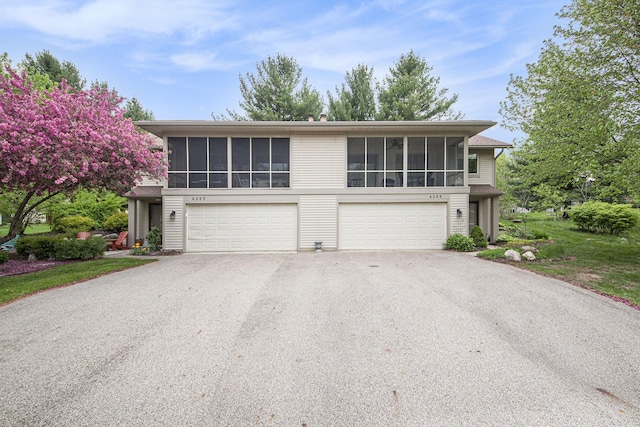4289 Millpond Dr NE, Rockford, MI 49341 - view of front facade featuring a sunroom, driveway, and a garage