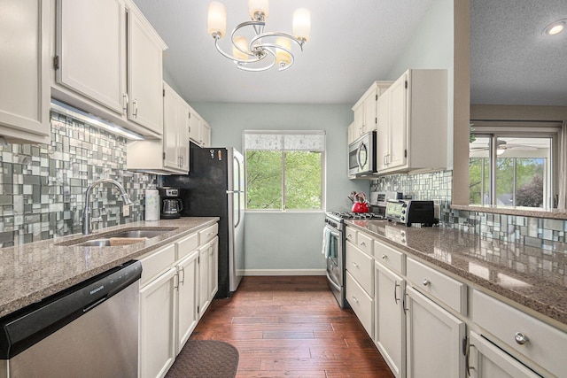 4289 Millpond Dr NE, Rockford, MI 49341 - kitchen with appliances with stainless steel finishes, a sink, baseboards, a chandelier, and decorative backsplash