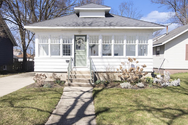 view of front facade featuring a front yard, a shingled roof, and entry steps