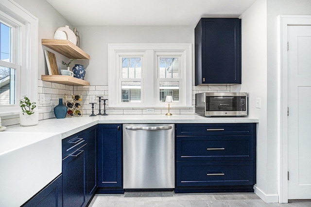 kitchen featuring open shelves, light countertops, tasteful backsplash, appliances with stainless steel finishes, and blue cabinetry