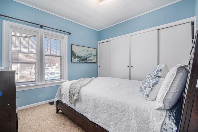 carpeted bedroom featuring crown molding, baseboards, and a closet