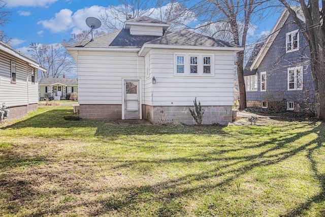 rear view of property with a lawn and a shingled roof