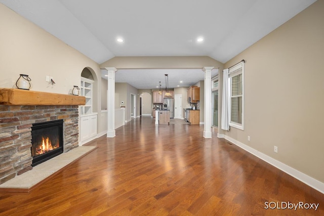 unfurnished living room featuring baseboards, decorative columns, a glass covered fireplace, and lofted ceiling