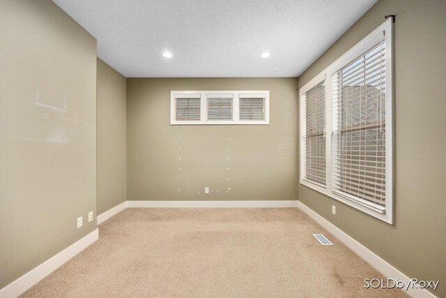 spare room with recessed lighting, baseboards, visible vents, and light carpet