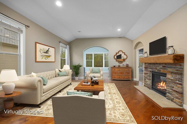 living room with arched walkways, a fireplace, vaulted ceiling, wood finished floors, and recessed lighting