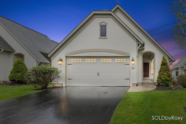 view of front of property with stucco siding, an attached garage, driveway, and a front yard