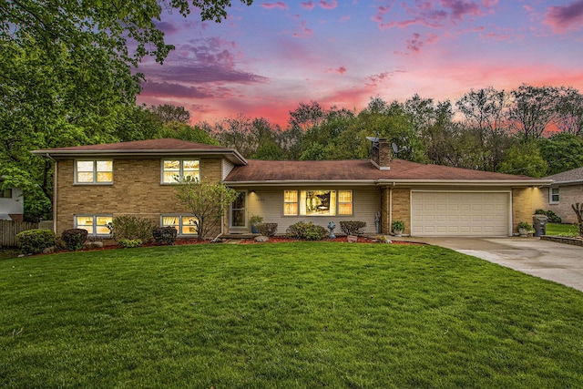 split level home with driveway, a chimney, a front yard, a garage, and brick siding