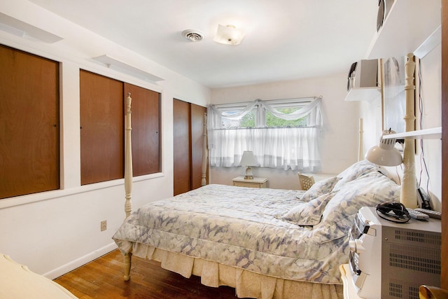 bedroom featuring multiple closets, baseboards, wood finished floors, and visible vents