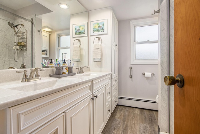 full bathroom featuring wood finished floors, walk in shower, a sink, and a baseboard radiator