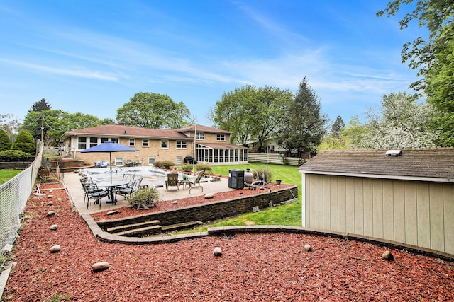 back of house featuring a sunroom, a shed, a fenced backyard, a patio area, and an outdoor structure