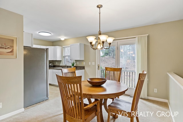 dining room featuring an inviting chandelier, baseboards, and light colored carpet