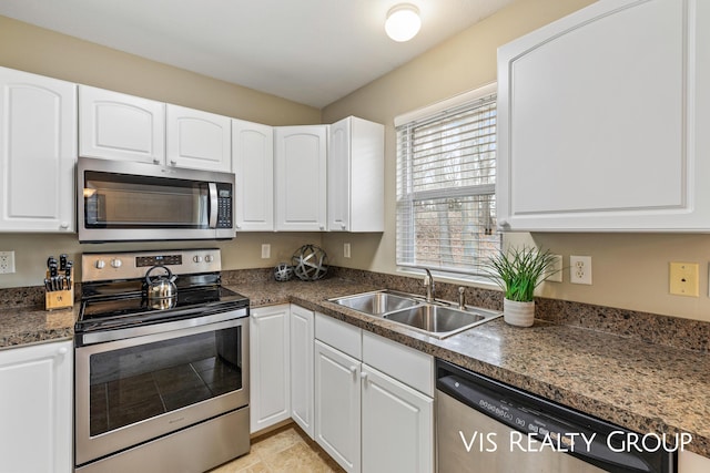kitchen featuring white cabinetry, dark countertops, appliances with stainless steel finishes, and a sink