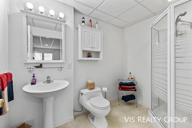 bathroom featuring baseboards, a drop ceiling, a shower stall, and toilet