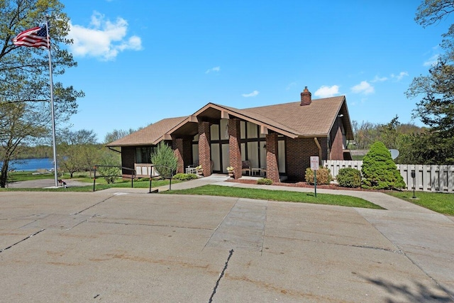 11771 Shenandoah Dr, Green Oak Twp, MI 48178 - view of front of house featuring fence, a chimney, brick siding, and concrete driveway