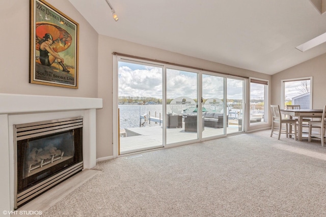 257 Shoreview Way Unit 9, Saint Joseph, MI 49085 - living room with lofted ceiling, carpet, a fireplace with flush hearth, rail lighting, and a water view