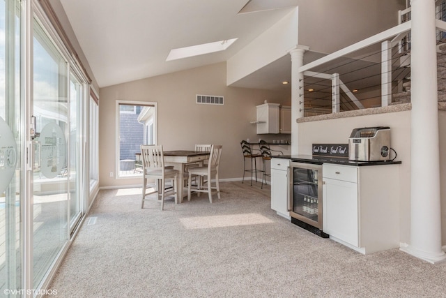 257 Shoreview Way Unit 9, Saint Joseph, MI 49085 - kitchen with wine cooler, light carpet, lofted ceiling, white cabinetry, and dark countertops
