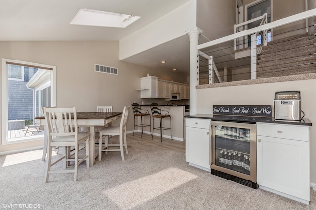 257 Shoreview Way Unit 9, Saint Joseph, MI 49085 - kitchen featuring beverage cooler, lofted ceiling, dark countertops, white microwave, and light colored carpet