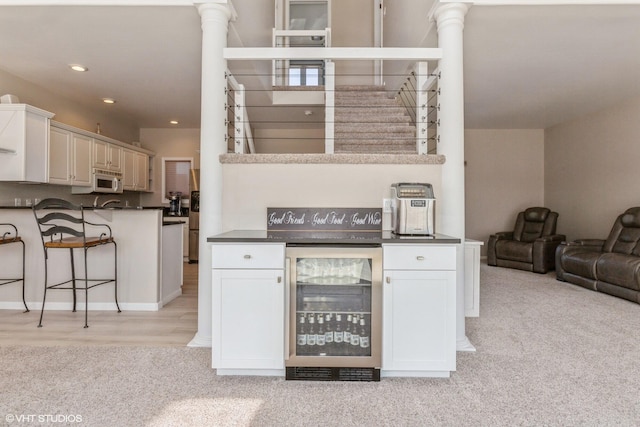 257 Shoreview Way Unit 9, Saint Joseph, MI 49085 - kitchen featuring wine cooler, white microwave, dark countertops, light carpet, and a breakfast bar